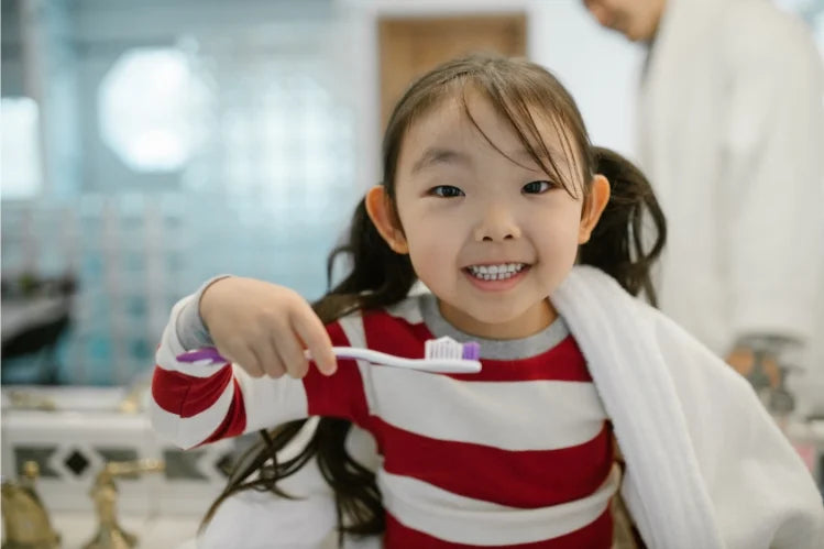 A child smiling and holding a toothbrush