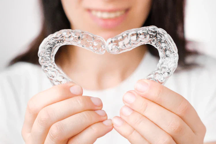A woman making a heart from clear aligners