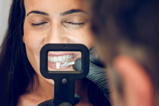 Dentist picking a sample of teeth veneer for a woman
