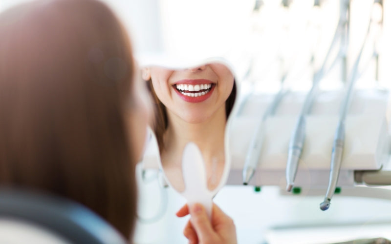 A women observes her teeth in a mirror