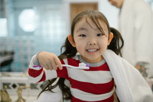 A child smiling and holding a toothbrush