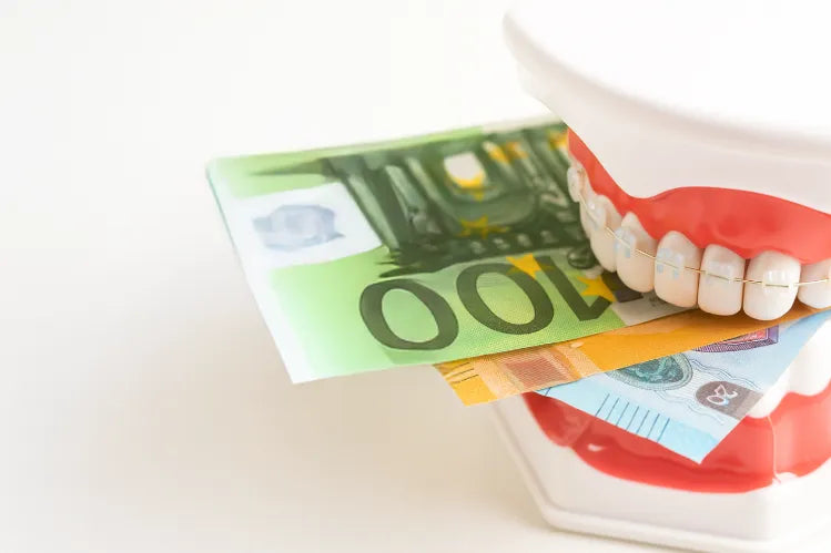 A teeth model with ceramic btraces with money between its teeth