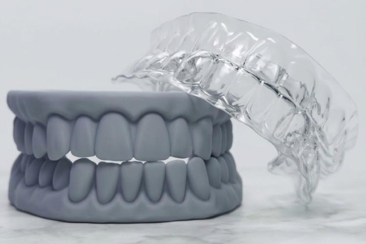 A grey dental model sits next to DIY retainers