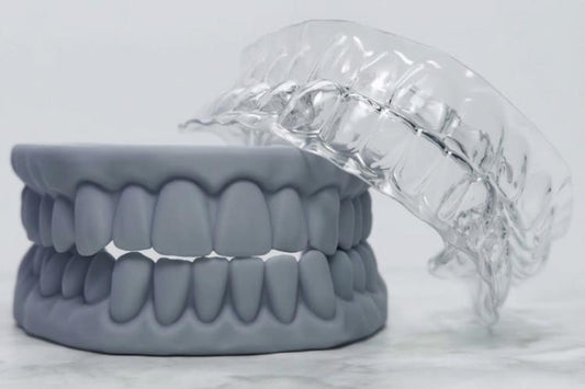A grey dental model sits next to DIY retainers