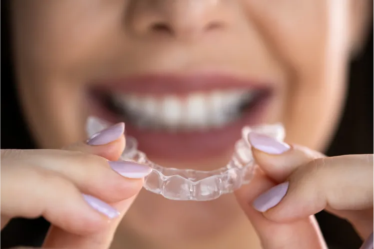 Woman holding clear aligners for adults.