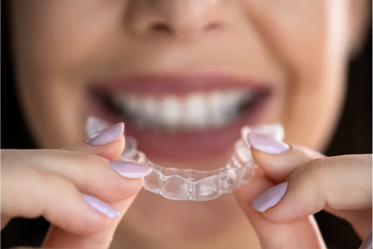 Woman holding clear aligners for adults.