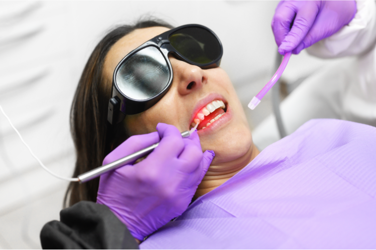 A dentist performing a laser treatment on a patient. 
