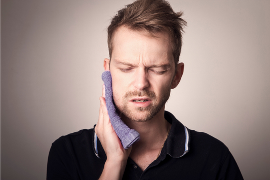  A man holding a cold compress to his jaw due to tooth pain