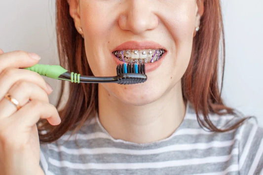 A woman brushing with braces applied to her teeth