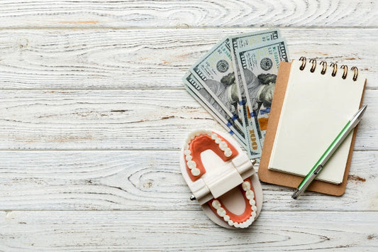 Ariel shot of paper currency, a teeth model, and a notepad on a table